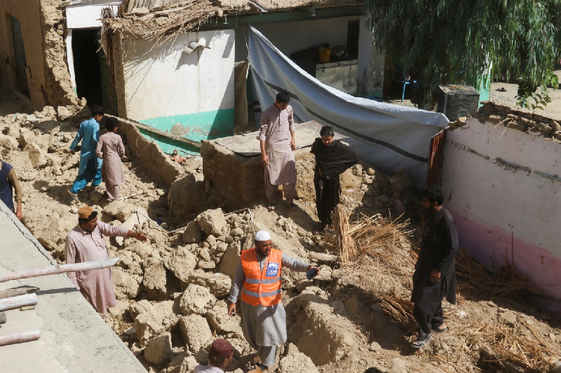 rescue workers and residents stand amid the rubble of a damaged house following the earthquake in harnai photo reuters
