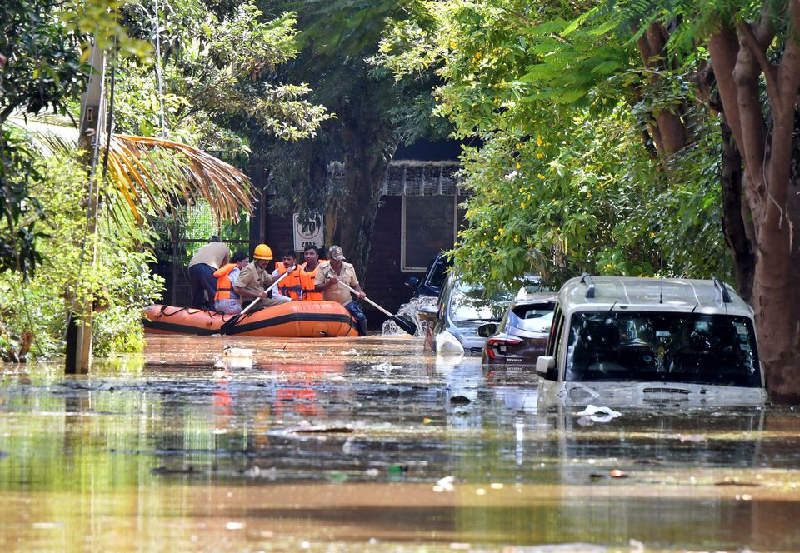 members of a rescue team row their boat past submerged vehicles following torrential rains in bengaluru india september 5 2022 photo reuters