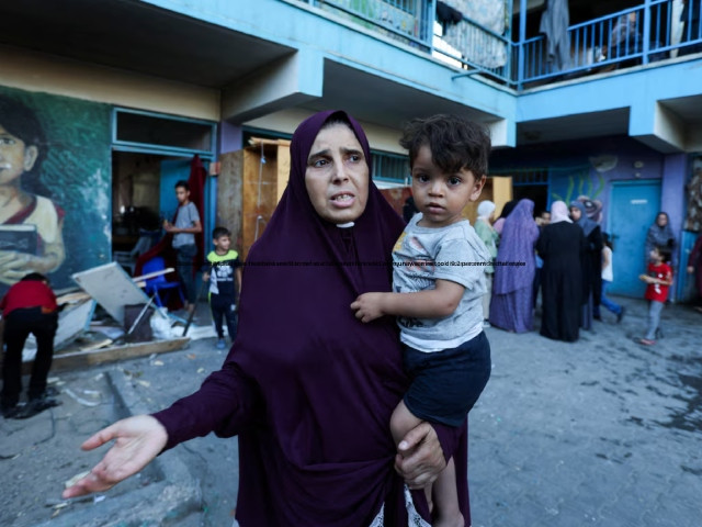 palestinian woman carrying a child reacts after an israeli air strike on a un school sheltering displaced people amid the israel hamas conflict in nusairat in central gaza strip july 6 2024 photo reuters