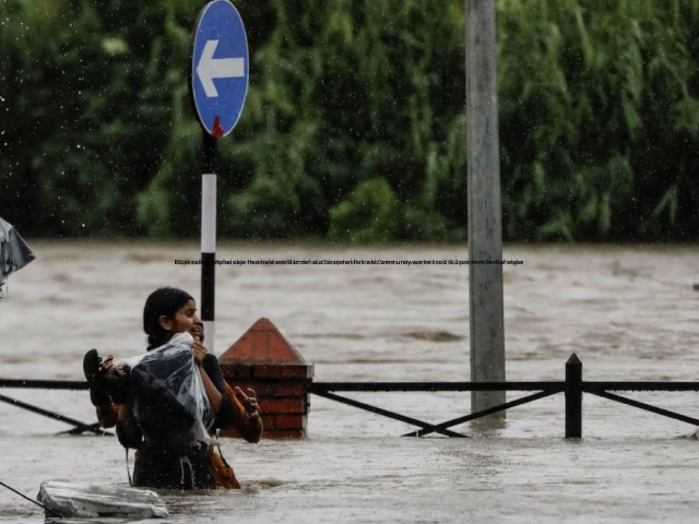 a woman carrying her belongings wades through a flooded road along the bank of overflowing bagmati river following heavy rains in kathmandu nepal july 6 2024 photo reuters