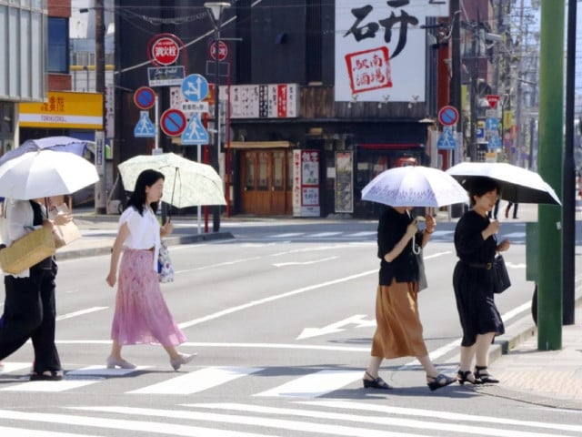 people walk under parasols in scorching heat in shizuoka on july 7 2024 with the central japan city recording a temperature of 40 c photo kyodo news