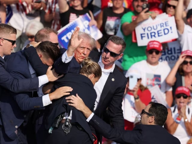 republican presidential candidate and former u s president donald trump gestures with a bloodied face while he is assisted by us secret service personnel after he was shot in the right ear during a campaign rally at the butler farm show in butler pennsylvania us july 13 2024 photo reuters