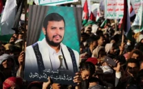 a person holds a placard with a picture of yemen s houthi movement leader abdul malik al houthi as supporters of the houthi movement rally to denounce air strikes launched by the u s and britain on houthi targets in sanaa yemen january 12 2024 ntsb handout via photo reuters