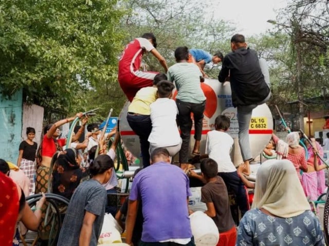 people rush to climb a water tanker as it arrives to deliver drinking water photo reuters