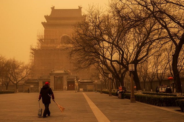 a person walks with a broom and dustpan during morning rush hour as beijing china is hit by a sandstorm march 15 2021 photo reuters