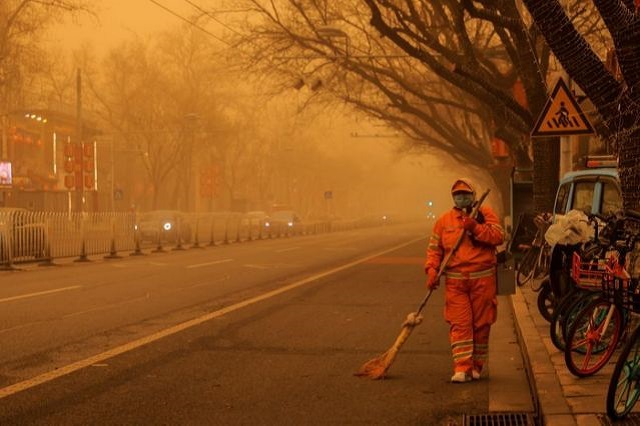 A sweeper walks with a broom along a road during morning rush hour as Beijing, China, is hit by a sandstorm, March 15, 2021. PHOTO: REUTERS