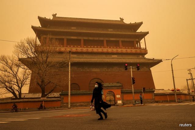 A woman walks past Drum Tower during morning rush hour as Beijing, China, is hit by a sandstorm, March 15, 2021. PHOTO: REUTERS