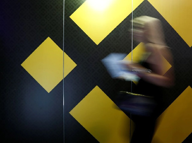 a woman walks past an exhibition stand showing the logo of binance at the delta summit in st julian s malta october 4 2018 photo reuters