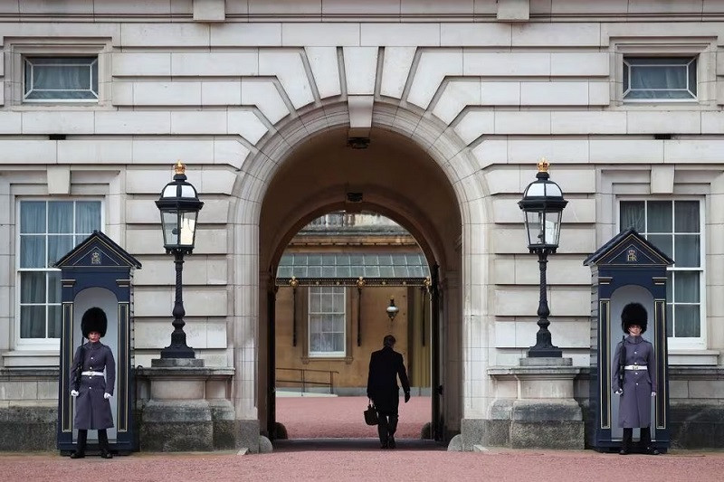 An employee walks at Buckingham Palace as guards stand outside, after it was announced that Britain's King Charles has been diagnosed with cancer, in London, Britain, February 6, 2024. PHOTO: REUTERS