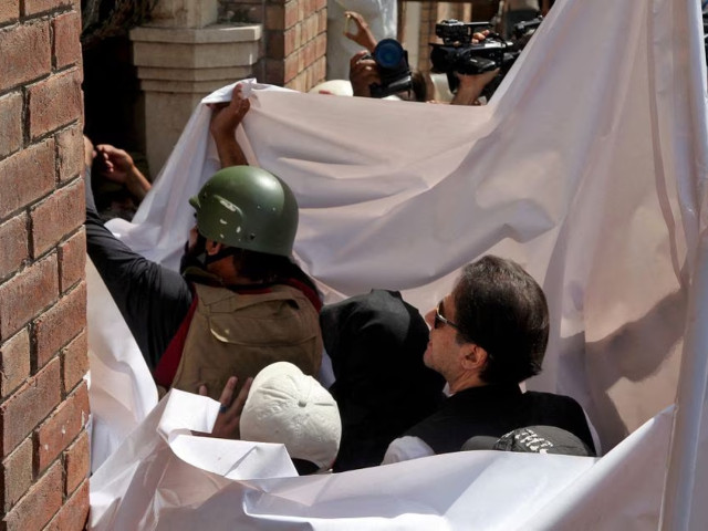 former prime minister imran khan and his wife bushra bibi are covered with a white sheet as they arrive to appear at the high court in lahore may 15 2023 photo reuters