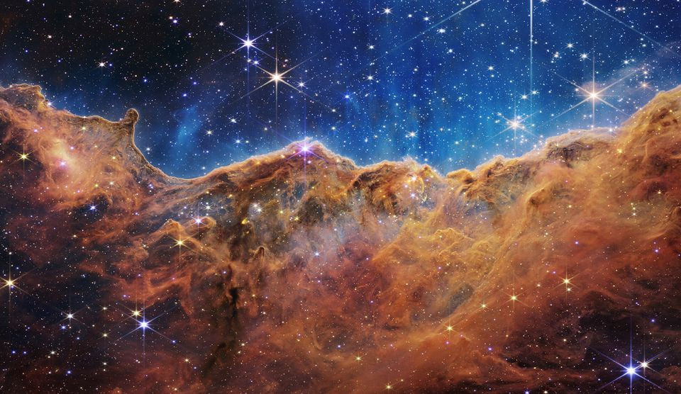 the cosmic cliffs of the carina nebula is seen in an image divided horizontally by an undulating line between a cloudscape forming a nebula along the bottom portion and a comparatively clear upper portion with data from nasa s james webb space telescope a revolutionary apparatus designed to peer through the cosmos to the dawn of the universe and released july 12 2022 photo reuters