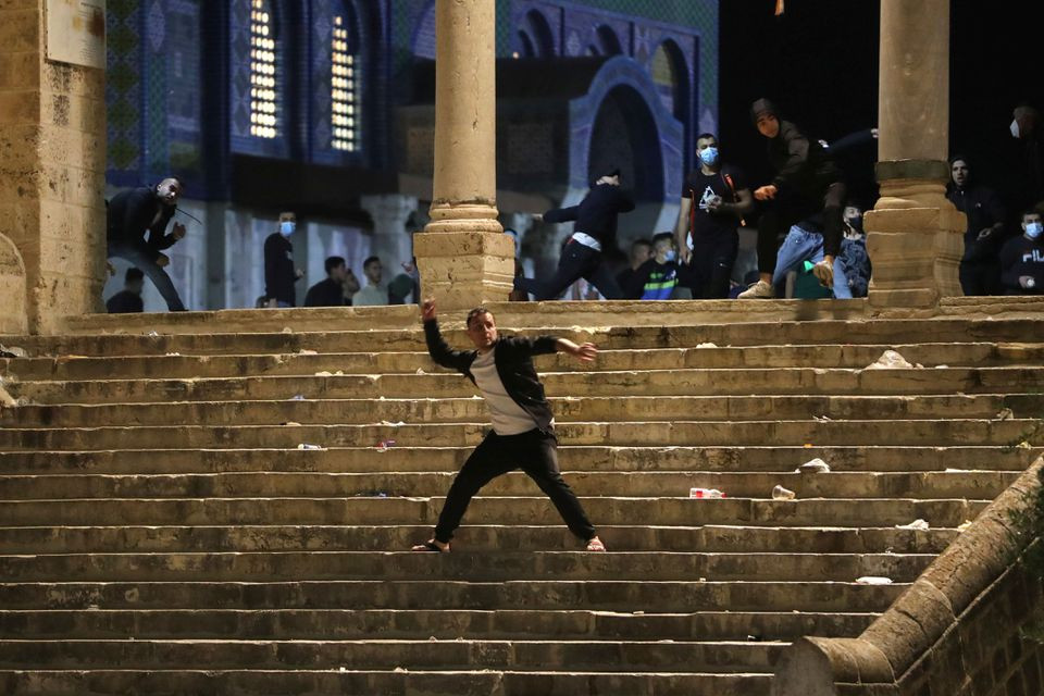 a palestinian hurls stones at israeli police during clashes at the compound that houses al aqsa mosque known to muslims as noble sanctuary and to jews as temple mount amid tension over the possible eviction of several palestinian families from homes on land claimed by jewish settlers in the sheikh jarrah neighbourhood in jerusalem s old city may 7 2021 reuters