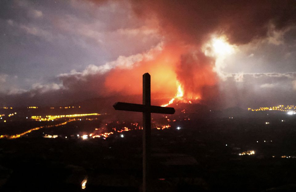 a cross is seen as lava and smoke rise following the eruption of a volcano on the island of la palma in los llanos de aridane spain september 21 2021 photo reuters