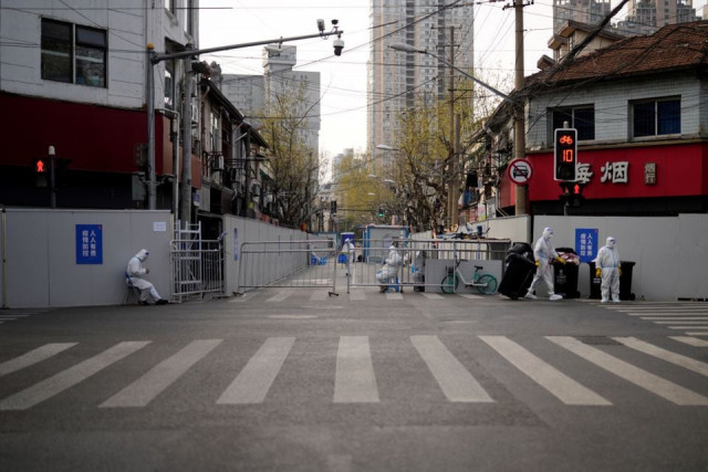 workers in protective suits keep watch at a sealed off area following the coronavirus disease covid 19 outbreak in shanghai china march 30 2022 reuters workers in protective suits keep watch at a sealed off area following the coronavirus disease covid 19 outbreak in shanghai china march 30 2022 reuters