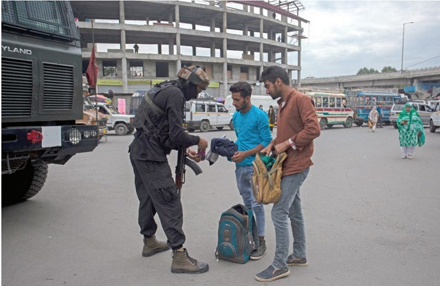 an indian security personnel searches bags of passers by along a street in srinagar on the eve of the second anniversary of the abrogation of article 370 photo afp