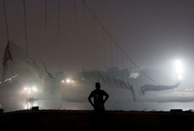 a security personnel stands near a damaged suspension bridge after it collapsed on sunday in morbi town in the western state of gujarat india november 1 2022 photo reuters a security personnel stands near a damaged suspension bridge after it collapsed on sunday in morbi town in the western state of gujarat india november 1 2022 photo reuters
