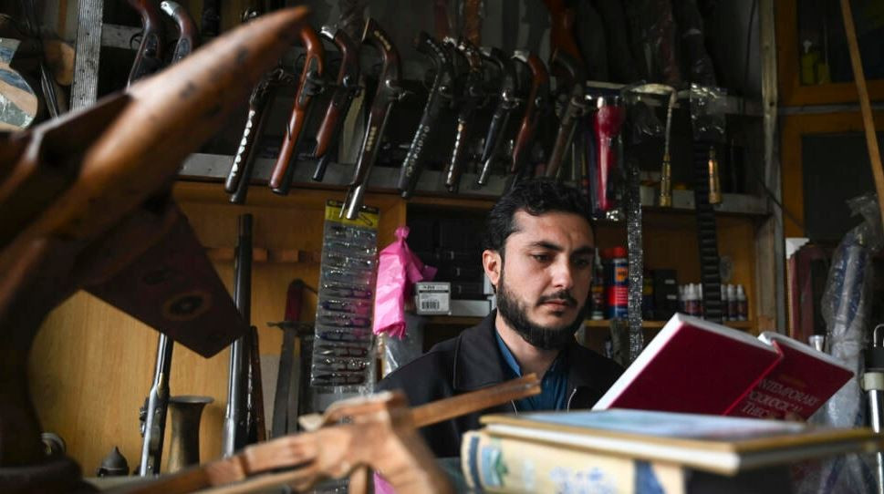 arms dealer muhammad jahanzeb reads a book at his shop in darra adamkhel about 35 kilometres south of peshawar photo afp