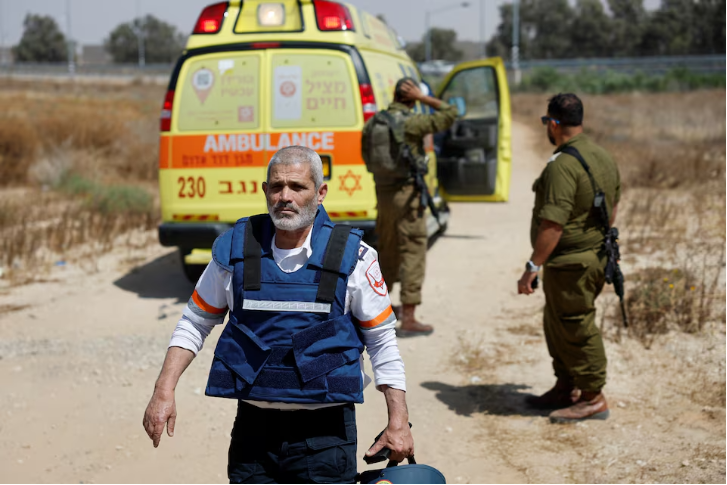 an israeli medic walks near soldiers and an ambulance after palestinian resistance group hamas claimed responsibility for an attack on kerem shalom crossing near israel s border with gaza in southern israel may 5 2024 photo reuters