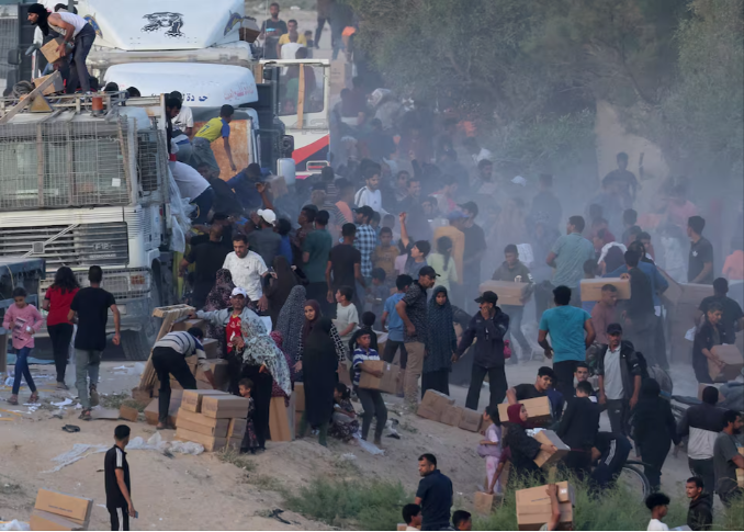 palestinians climb onto trucks to grab aid that was delivered into gaza through a u s  built pier amid the ongoing conflict between israel and the palestinian islamist group hamas as seen from central gaza strip may 18 2024 reuters ramadan abed file photo