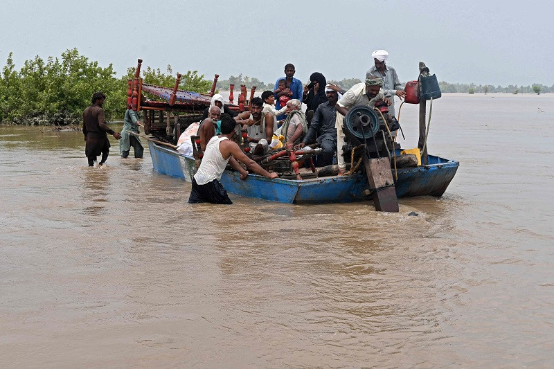 People with their belongings wade through the flood affected area of Chanda Singh Wala village in Kasur district on August 22, 2023. PHOTO: AFP