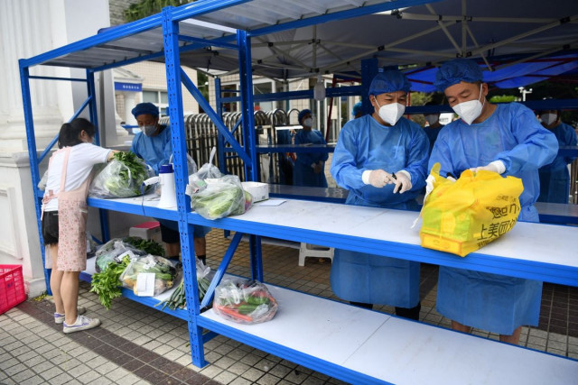 workers in protective suits prepare to deliver food supplies placed on a rack outside a residential compound to its residents amid a lockdown to curb the coronavirus disease covid 19 outbreak in chengdu sichuan province china cnsphoto via reuters workers in protective suits prepare to deliver food supplies placed on a rack outside a residential compound to its residents amid a lockdown to curb the coronavirus disease covid 19 outbreak in chengdu sichuan province china cnsphoto via reuters