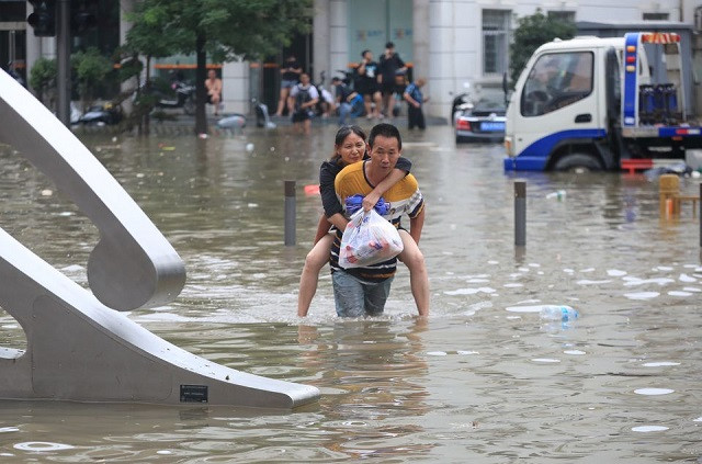 A man carrying a woman wades through a flooded road following heavy rainfall in Zhengzhou, Henan province, China July 21, 2021. PHOTO: REUTERS