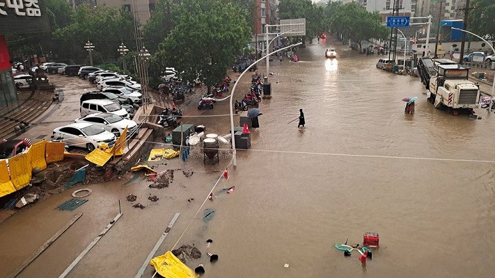 People wade through floodwaters on a road amid heavy rainfall in Zhengzhou, Henan province, China July 20, 2021. PHOTO: REUTERS