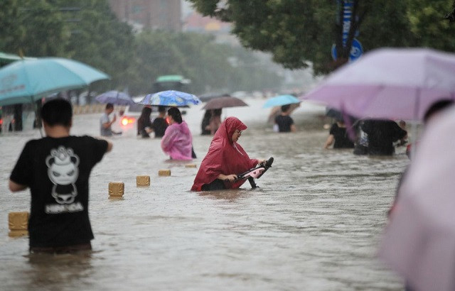 Residents wade through floodwaters on a flooded road amid heavy rainfall in Zhengzhou, Henan province, China July 20, 2021. PHOTO: REUTERS