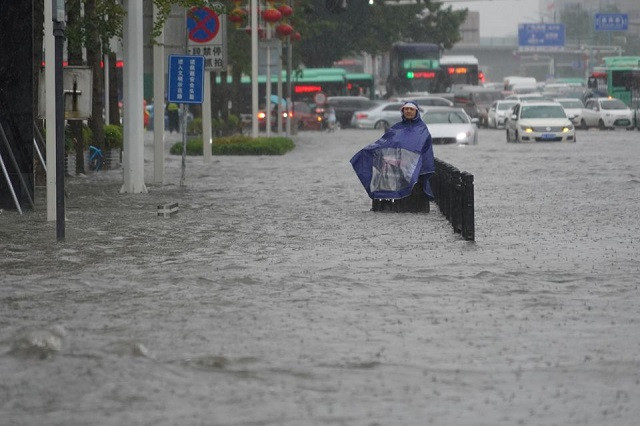 A resident wearing a rain cover stands on a flooded road in Zhengzhou, Henan province, China July 20, 2021. PHOTO: REUTERS