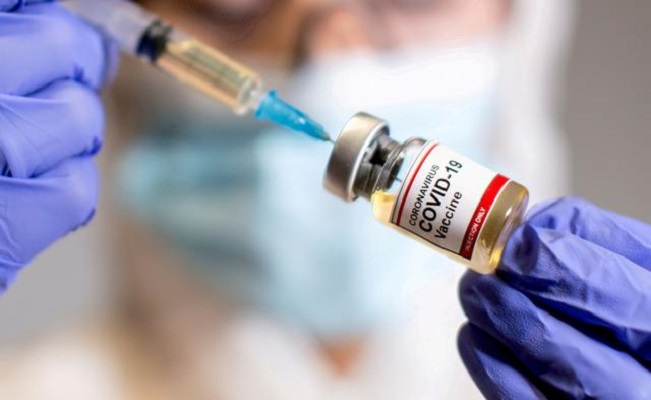 a woman holds a small bottle labelled with a coronavirus covid 19 vaccine sticker and a medical syringe in this illustration taken october 30 2020 photo reuters