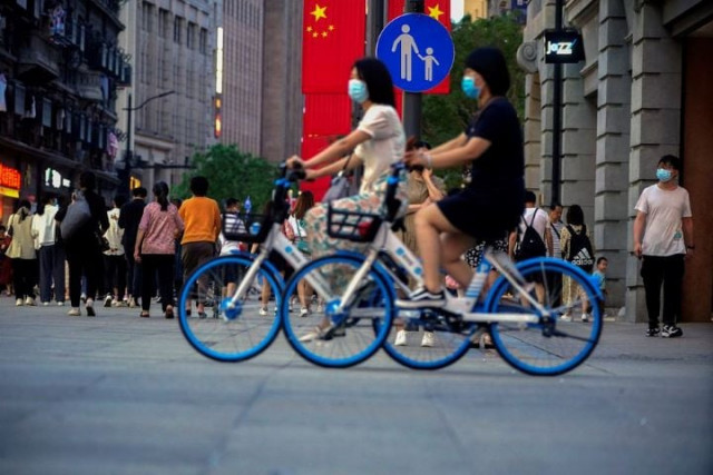 woman ride bikes on a street following the outbreak of the coronavirus disease covid 19 in shanghai china may 10 2021 photo reuters woman ride bikes on a street following the outbreak of the coronavirus disease covid 19 in shanghai china may 10 2021 photo reuters