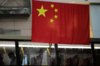 a passenger rides on a bus travelling past a chinese flag in the rain before the 25th anniversary of the former british colony s handover to chinese rule in hong kong china june 30 2022 photo reuters