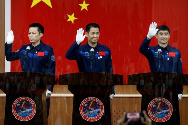 chinese astronauts nie haisheng liu boming and tang hongbo wave as they meet members of the media behind a glass wall before the shenzhou 12 mission to build china s space station at jiuquan satellite launch center near jiuquan gansu province china june 16 2021 photo reuters