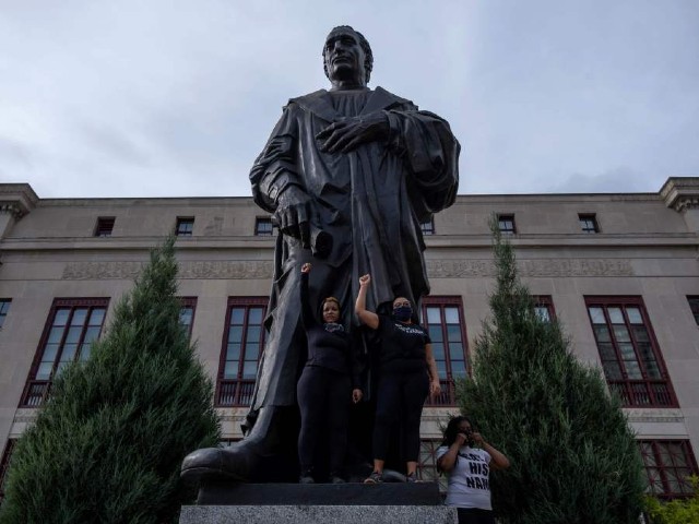 protesters raise their fists as they stand on the base of a statue of christopher columbus in front of city hall during an international march for black lives protest against police brutality in downtown columbus ohio photo afp file