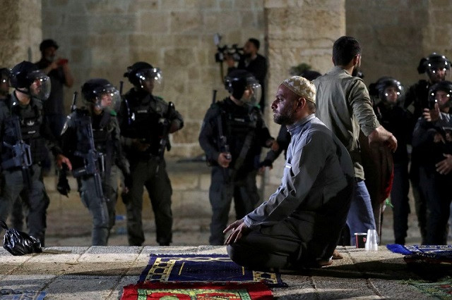 A Palestinian man prays as Israeli police gather during clashes at the compound that houses Al-Aqsa Mosque, known to Muslims as Noble Sanctuary and to Jews as Temple Mount, amid tension over the possible eviction of several Palestinian families from homes on land claimed by Jewish settlers in the Sheikh Jarrah neighbourhood, in Jerusalem's Old City, May 7, 2021. PHOTO: REUTERS