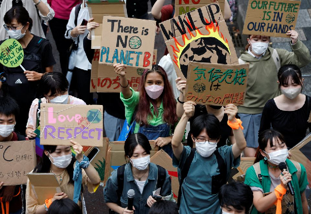 people raise placards as they take part in a global climate protest march at omotesando district in tokyo japan september 23 2022 photo reuters