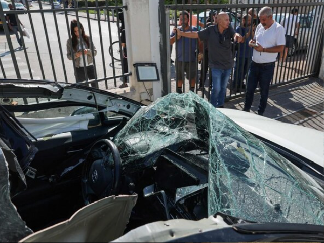 people look at a damaged car where an artillery shell fell before it was removed by israeli police in raanana near tel aviv on nov 6 2024 following a reported barrage of rockets launched from lebanon toward israel photo afp