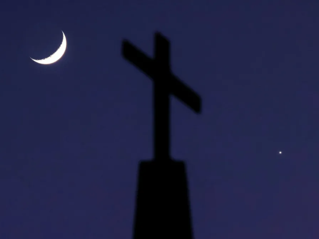 A crescent Moon and the planet Venus straddle a cross on top of Quebec Baptist Church in Ellaville, Georgia. Reuters