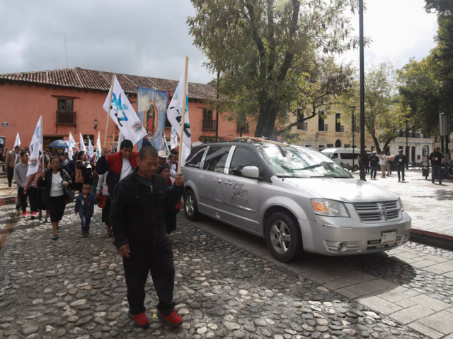 People walk next to a hearse carrying the coffin with the body of priest Marcelo Perez, through the streets in San Cristobal de las Casas, where he was killed on Sunday after officiating a mass, in San Cristobal de las Casas in the southern state of Chiapas, Mexico, October 20, 2024. REUTERS/Gabriela Sanabria