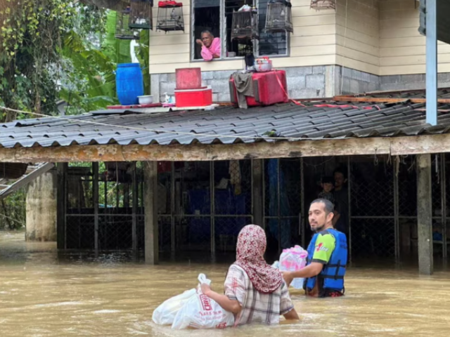 A rescue worker delivers bottled water to people staying in flooded houses in Sateng Nok, Yala Province, Thailand, November 30, 2024, in this picture obtained from social media. Poh Teck Tung Foundation/via REUTERS