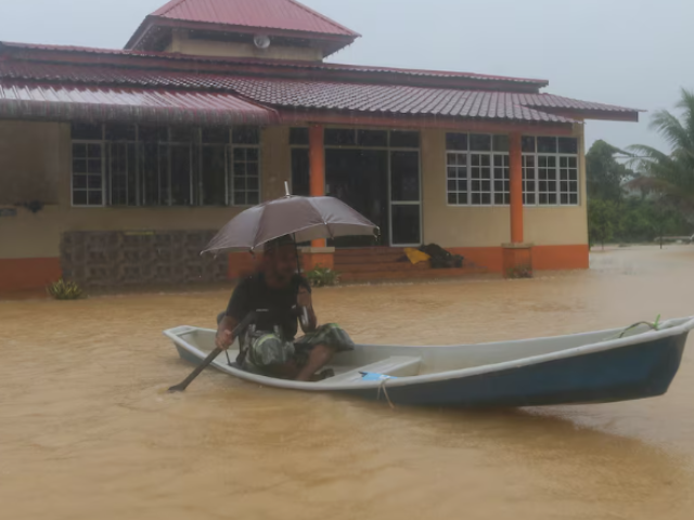 A man paddles a boat through floodwaters after performing prayers at a mosque in Hulu Terengganu, Malaysia, November 29, 2024. REUTERS/ Stringer