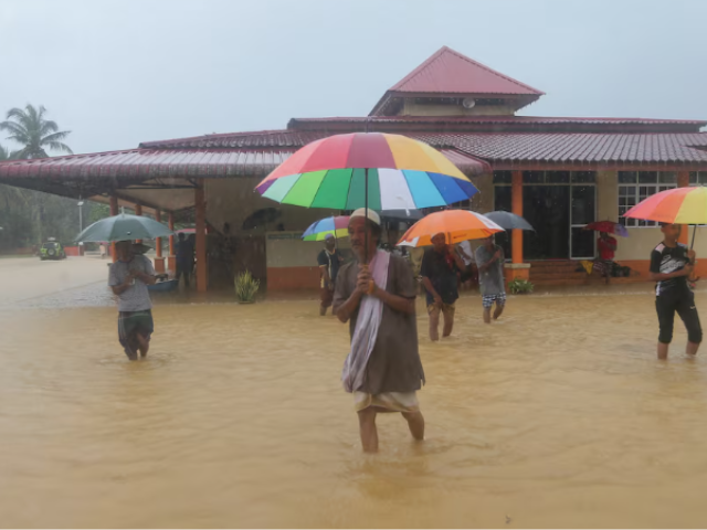 Men wade through floodwaters after performing prayers at a mosque in Hulu Terengganu, Malaysia, November 29, 2024. REUTERS/ Stringer