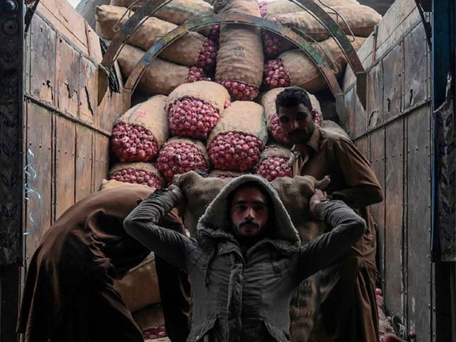 labourers carry sacks of onions from a truck at a market in lahore photo afp