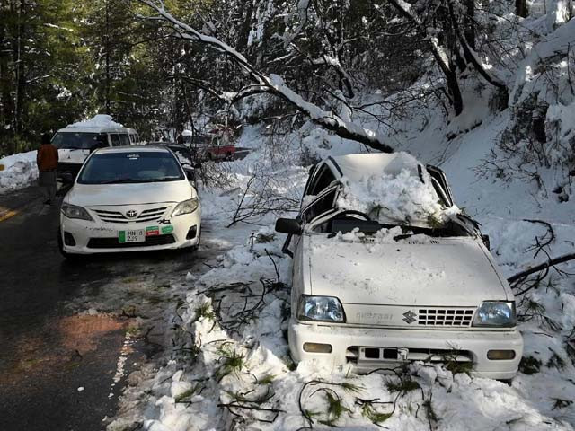 an army soldier stands near a damaged car during a rescue operation to clear roads in murree photo afp