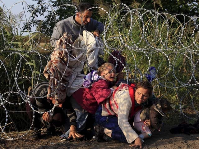 refugees at a barbed wire fence photo reuters