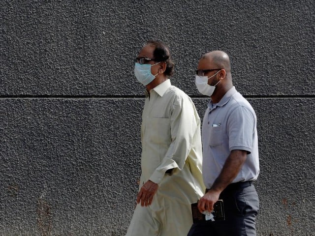 men walk with face masks as a preventive measure after pakistan confirmed its first two cases of coronavirus along a sidewalk in karachi pakistan photo reuters file