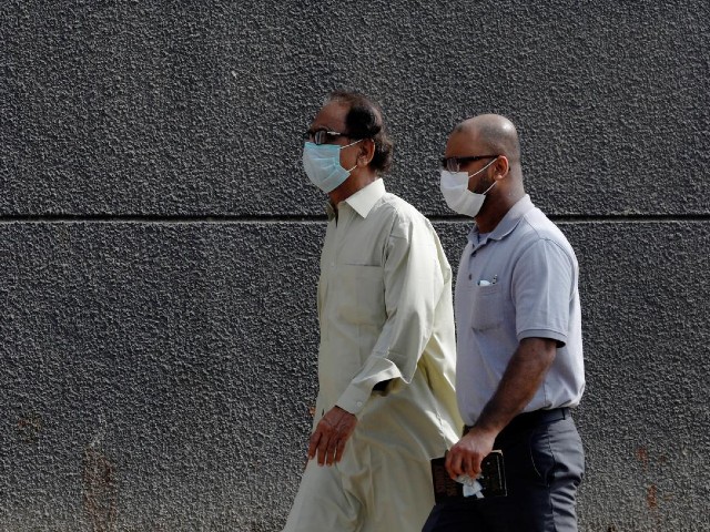 Men walk with face masks as a preventive measure, after Pakistan confirmed its first two cases of coronavirus, along a sidewalk in Karachi, Pakistan. PHOTO: REUTERS/FILE