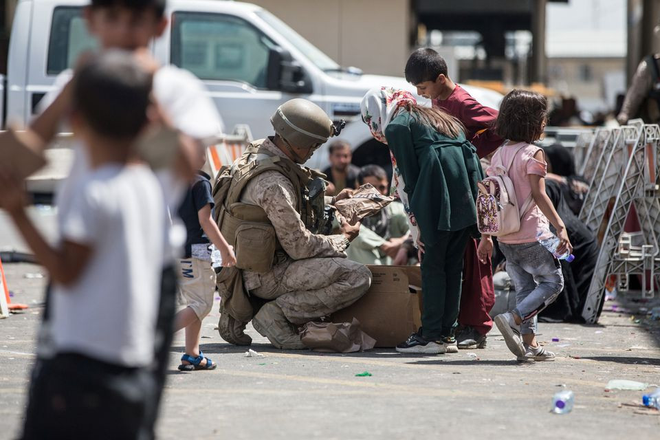 A U.S. Marine provides meals ready-to-eat to a child during an evacuation at Hamid Karzai International Airport, Kabul, Afghanistan, August 21, 2021. Picture taken August 21, 2021. U.S. Marine Corps/Sgt. Samuel Ruiz/Handout via REUTERS