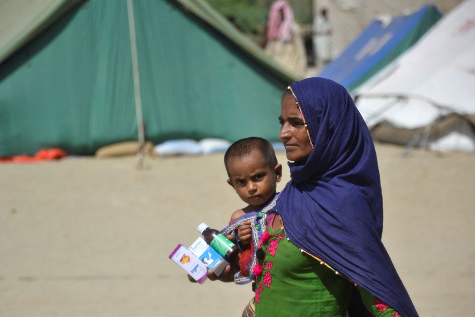 a woman displaced because of the floods carry a boy and medicines as she takes refuge in a camp following rains and floods during the monsoon season in sehwan pakistan september 20 2022 reuters