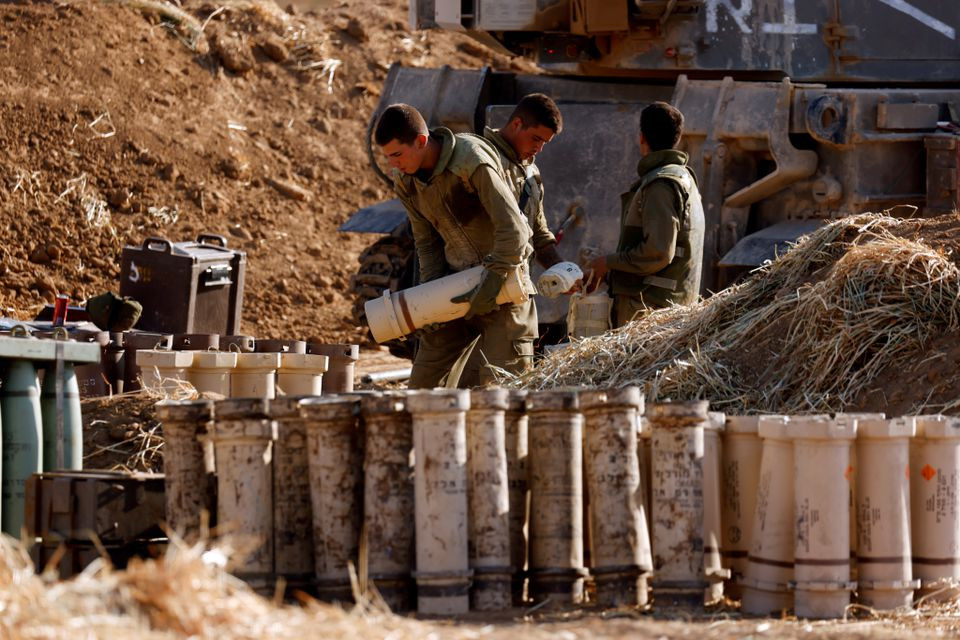 Israeli soldiers work by their mobile artillery unit near the border between Israel and the Gaza Strip. PHOTO: REUTERS